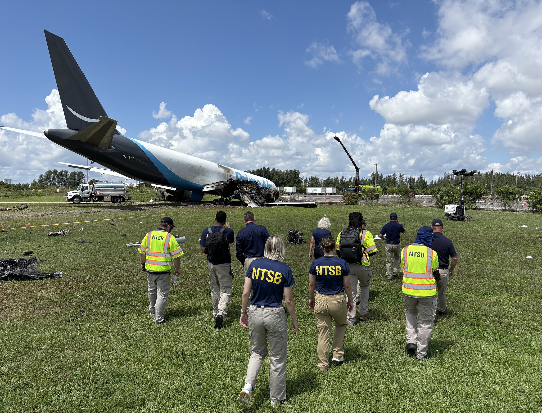 NTSB-onderzoekers lopen op 7 september 2026 door het gras naar het beschadigde vrachtvliegtuig in Miami.